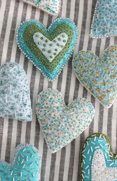 several blue and white heart shaped cookies on a striped tablecloth with sprinkles