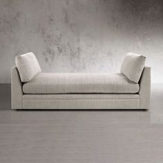 a white couch sitting on top of a hard wood floor next to a gray wall