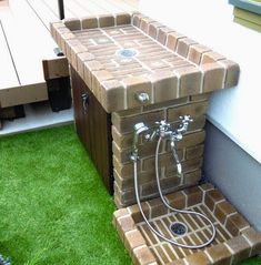 an outdoor shower in the grass next to a wooden deck