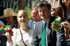 a man and woman standing next to each other in front of a crowd holding flowers