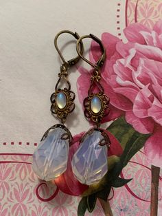 These Art Nouveau style earrings are handmade.  They feature a Swarovski crystal white opal and also a smaller opal cabochon in a filigree setting.  These earrings measure 1/2 inch wide and 2 inches in length.  The closure is a brass lever back but can be converted to wires upon your request. Adjustable Nickel-free Opal Earrings, Elegant Cabochon Adjustable Earrings, Vintage Iridescent Earrings For Gift, Handmade White Victorian Earrings, Handmade Victorian White Earrings, White Victorian Handmade Earrings, Elegant Adjustable Opal Earrings, Nickel-free White Victorian Jewelry, Handmade Vintage Opal Jewelry