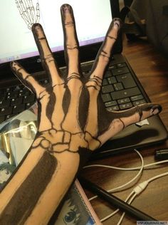 a person's hand painted with black and white paint on their left arm next to a laptop computer