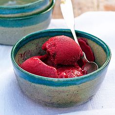 two bowls filled with red ice cream on top of a white cloth covered tablecloth