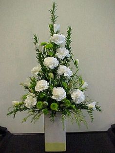 a vase with white flowers and greenery in it