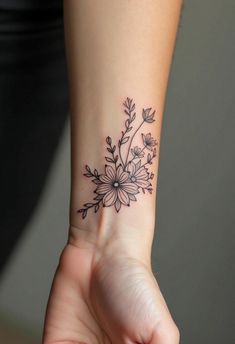 a woman's wrist tattoo with flowers and leaves on her left hand, in black ink