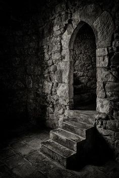 an old stone building with stairs leading up to the door and light coming through it