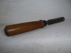 an old wooden knife with a black handle on a white tableclothed surface next to it