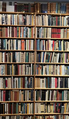 a bookshelf filled with lots of different colored books on top of wooden shelves