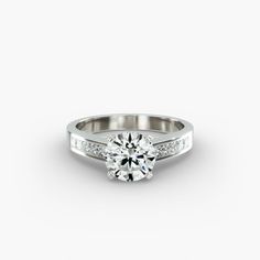 a white gold engagement ring with channel set diamonds on the sides and a round center stone