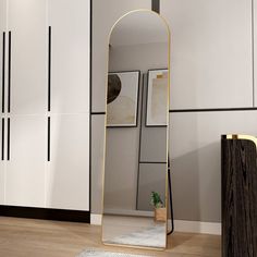 a large mirror sitting on top of a wooden floor next to a white cabinet and door