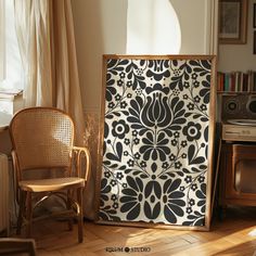 a chair sitting next to a wall covered in black and white tiles on top of a hard wood floor