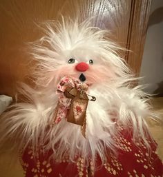 a stuffed animal that is wearing a red and white dress with feathers on it's chest