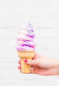 a hand holding an ice cream cone with sprinkles