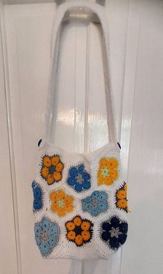 Cute crochet tote bag made with the African flower design. Colourful flowers joined with white. Handle adorned with 2 blue buttons Made in acrylic yarn Made in a smoke free environment  Ready to dispatch White Square Crochet Bag For Vacation, White Square Crochet Bag For Beach, Handmade White Crochet Bag For Daily Use, White Granny Square Crochet Bag For Everyday Use, White Crochet Bags For Vacation, White Handmade Crochet Bag For Daily Use, White Flower Shoulder Bag For Everyday Use, White Crochet Shoulder Bag For Vacation, White Granny Square Bag For Everyday Use