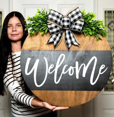 a woman holding a welcome sign in front of a door