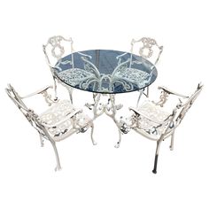 a glass table and four chairs with white wrought iron frame around the top, set against a white background