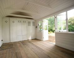 an empty room with wooden floors and white doors on the walls, windows in the ceiling, and wood flooring