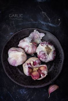 garlic on a black plate with three heads