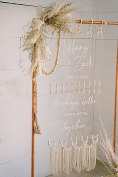 a wedding sign hanging on the side of a white wall next to some dried flowers