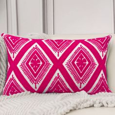 a pink and white pillow sitting on top of a couch