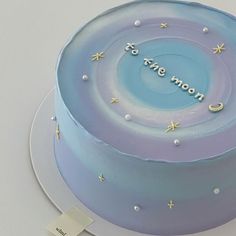 there is a blue cake with stars and moon designs on the top that says to the moon