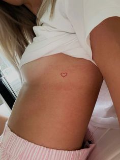 a woman with a small heart tattoo on her stomach