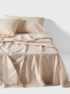 an unmade bed with pink and white striped sheets