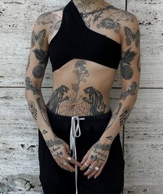 a woman with tattoos standing in front of a wall