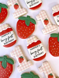 decorated cookies are arranged in the shape of numbers and strawberries for a first birthday