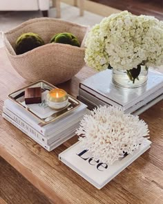 a table topped with books and vases filled with white hydrangeas on top of each other