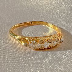 a yellow gold ring with three diamonds on it's sides, sitting on a white cloth