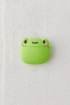 a green frog shaped object hanging from the side of a white wall with drops of water on it