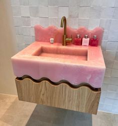 a pink sink with gold faucet and soap dispenser