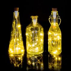 three glass bottles with lights in them