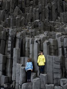 two children standing on the edge of a large rock formation, with their eyes closed