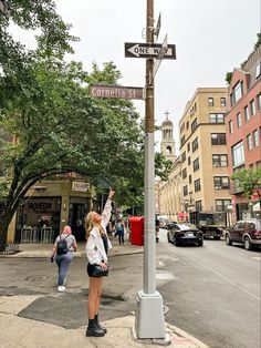 a woman points at the corner of an intersection