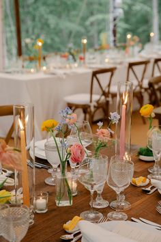 the table is set with flowers, candles and place settings for an elegant dinner party