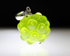 a close up of a ring made out of green beads on a white surface with a black background