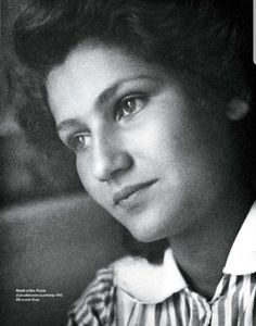 a black and white photo of a woman with short hair wearing a striped shirt looking at the camera