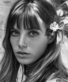 a young woman with long hair and flower in her hair is looking at the camera