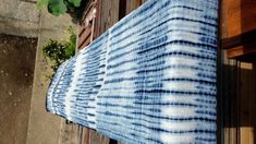 a blue and white tie - dyed cloth hanging from a window sill in front of a building