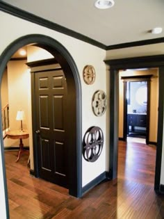 an entry way with black doors and wooden floors