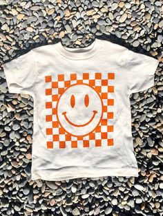 Kids Happy Face, Checkerboard Tee! The Details: - super soft kids t-shirt in Bella Canvas kids, airlume jersey, 100% cotton - color: Natural (Please note this is not white!) - ink color: burnt orange  - this item is SCREEN PRINTED which keeps the graphic soft and also allows you to toss in washer and dryer without worry! - we do recommend turning inside out when washing for longest life! - this shirt is 100% cotton so it may shrink about an inch all the way around when laundered Kids are loving Diy Checkerboard, Colorful Checkerboard, School Tees, Happy Face, Kid Tees, White Ink, Washer And Dryer, Kids Tops, Ink Color