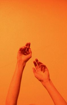 two hands reaching up into the air to catch a frisbee