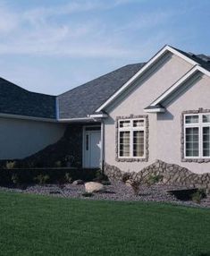 a house that is in the grass with rocks on the front and side of it