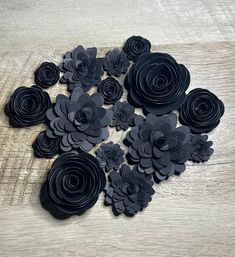 black paper flowers are arranged on a wooden surface