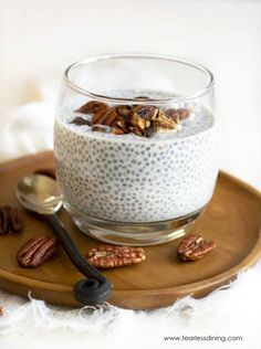 chia seed pudding with pecans in a glass bowl on a wooden serving tray