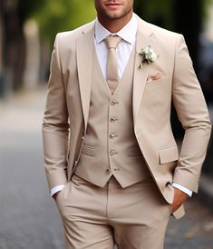 a man in a tan suit and white shirt is standing on the street with his hands in his pockets