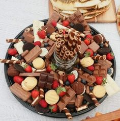 a platter filled with assorted chocolates and strawberries next to sliced bread