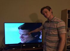 a man standing in front of a flat screen tv with the image of edward snow on it